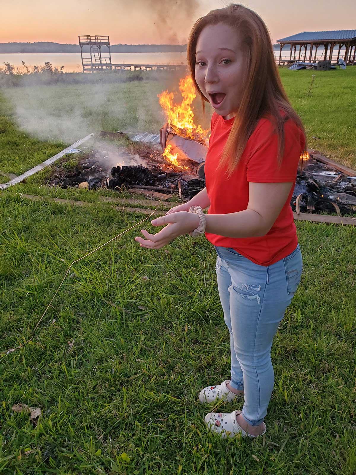 photo of girl with amused expression standing in front of fire