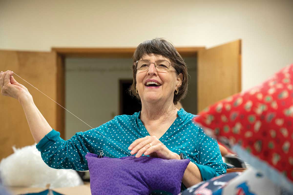 Susan Scott sews pillows with other volunteers