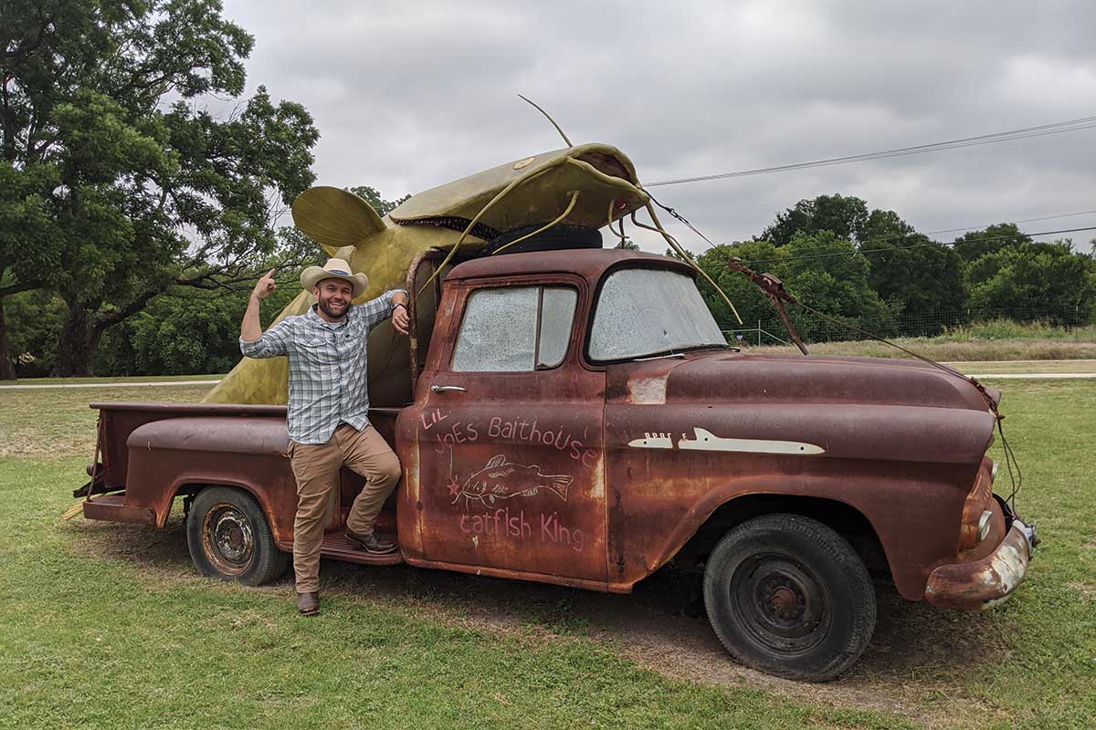 Chet stands in front of an old truck with a giant catfish in the bed