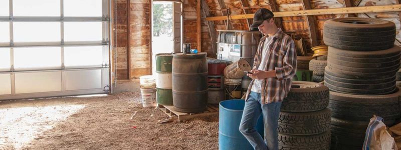 A young farmer looking at a cell phone in a barn