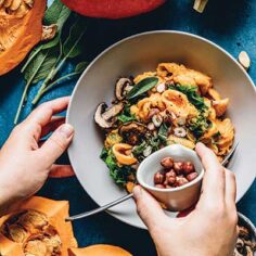 woman's hand adding ingredients to a savory pumpkin entree