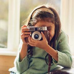 A young girl shooting with a vintage camera