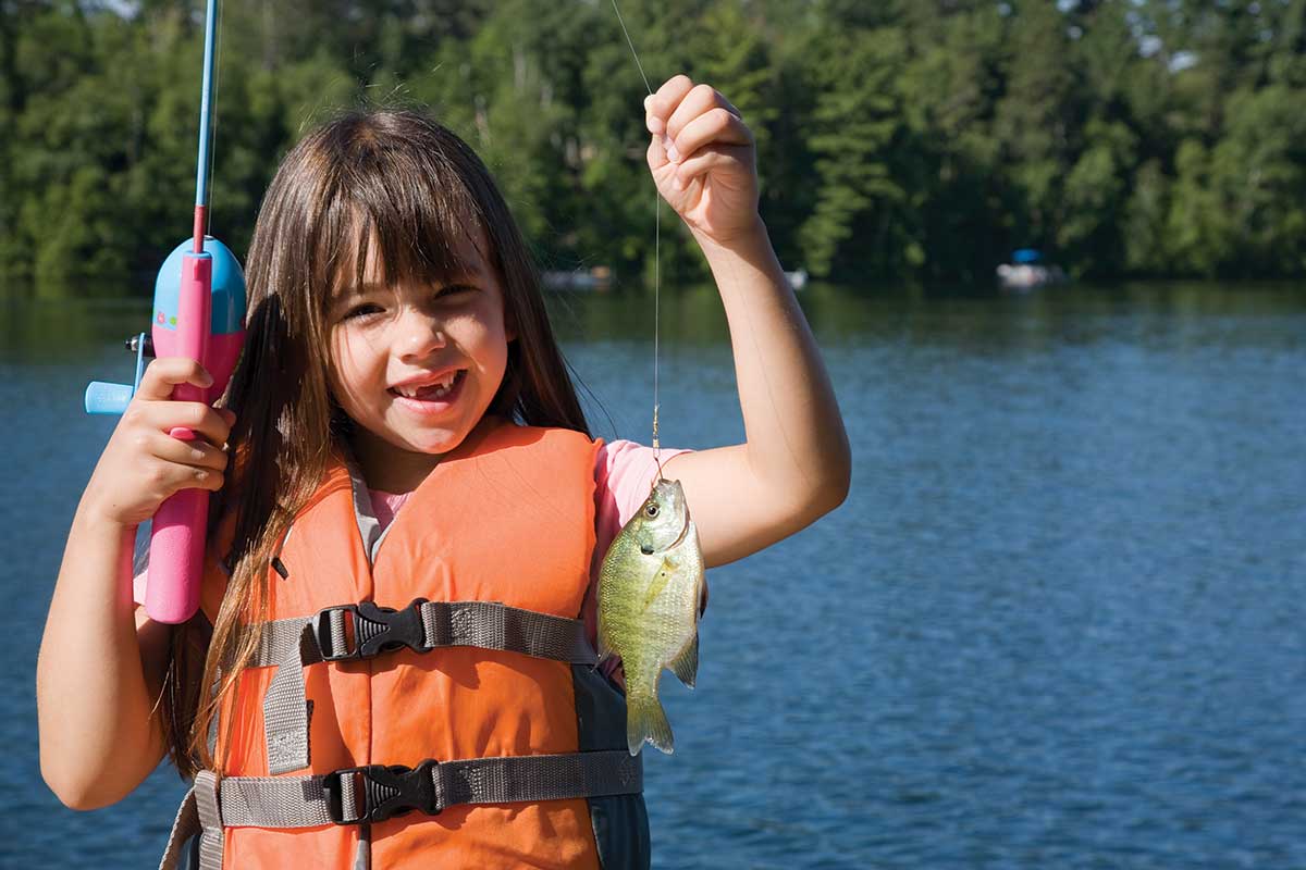 A young girl holds a fish she just caught