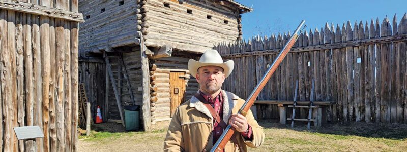 Chet in frontier garb with a rifle at Old Fort Parker in Groesbeck