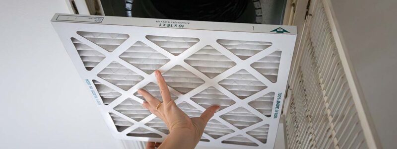 Hands replacing an air conditioning filter