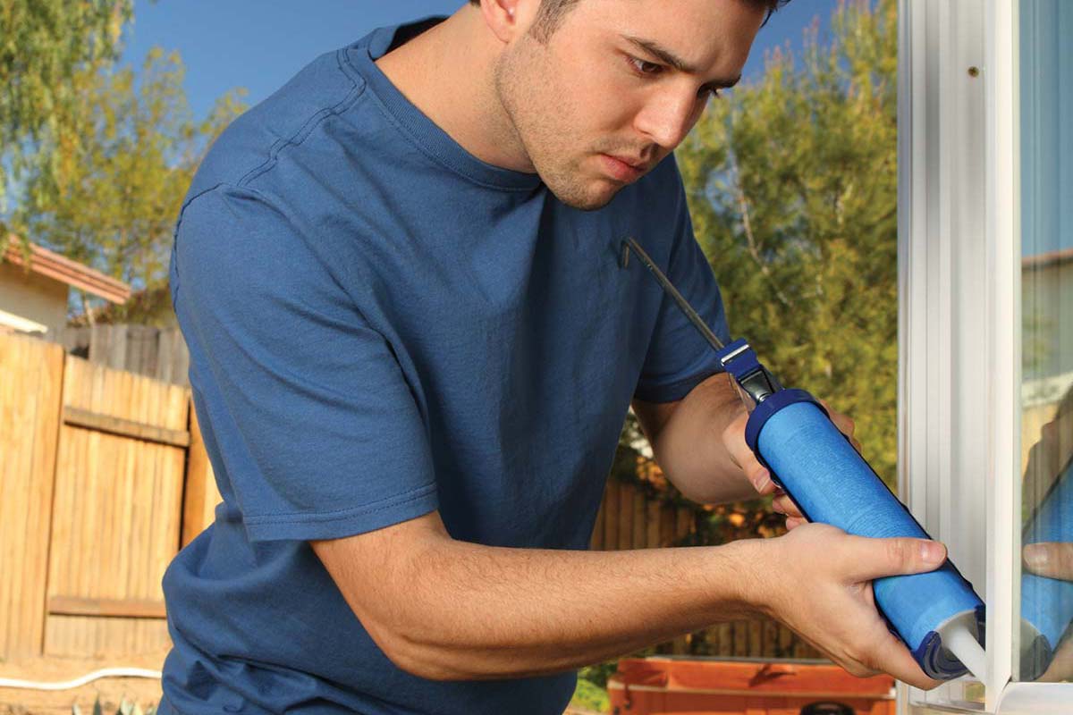 a man caulking a window